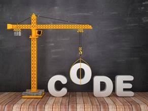 Construction crane lifting the word CODE against a chalkboard background, representing coding in infrastructure development