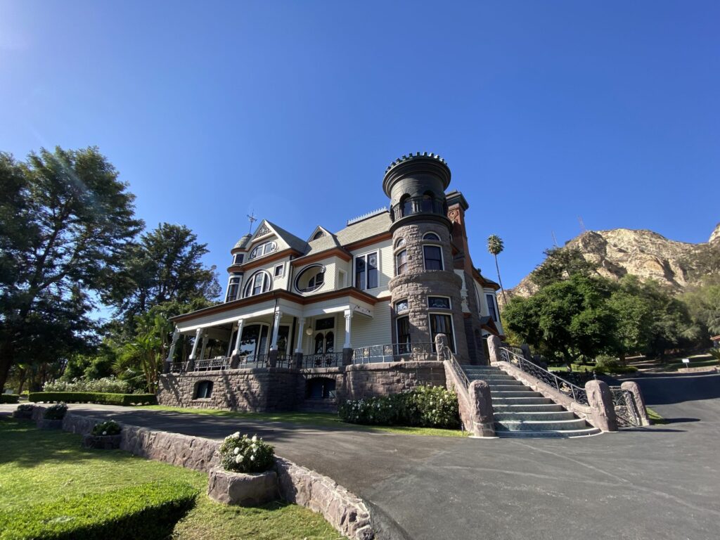 Side view of a Victorian-style house with a round tower and wrap-around porch