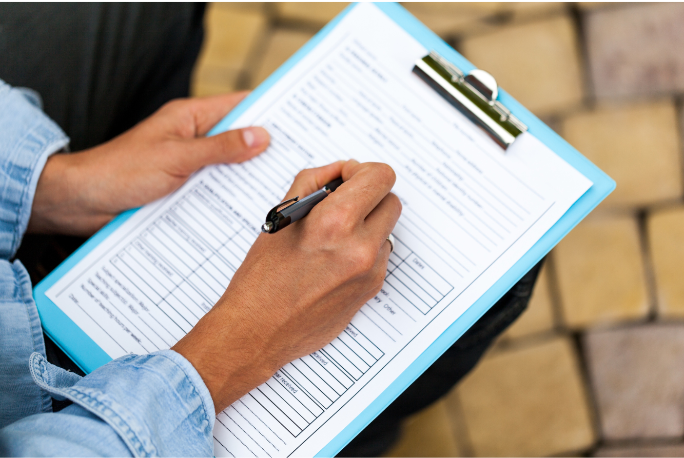 Person filling out a form on a clipboard.