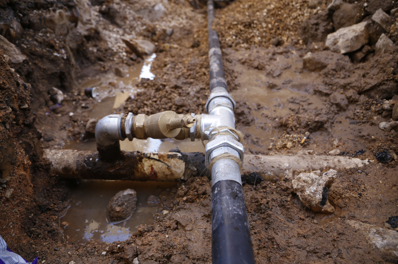 Underground water pipe in a muddy trench.