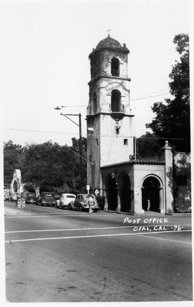 Black and white historical photo of Ojai Post Office Tower and Portico with vintage cars parked along the street.