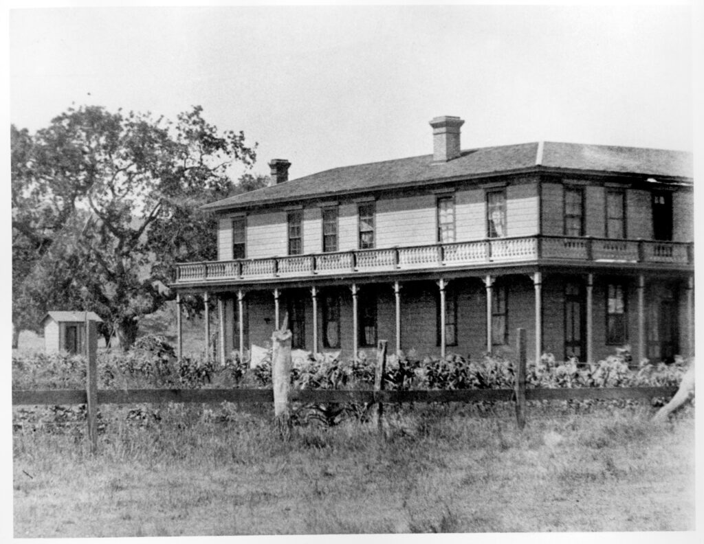 Historical black and white photo of the Stagecoach Inn, featuring two-story structure with wraparound porch.