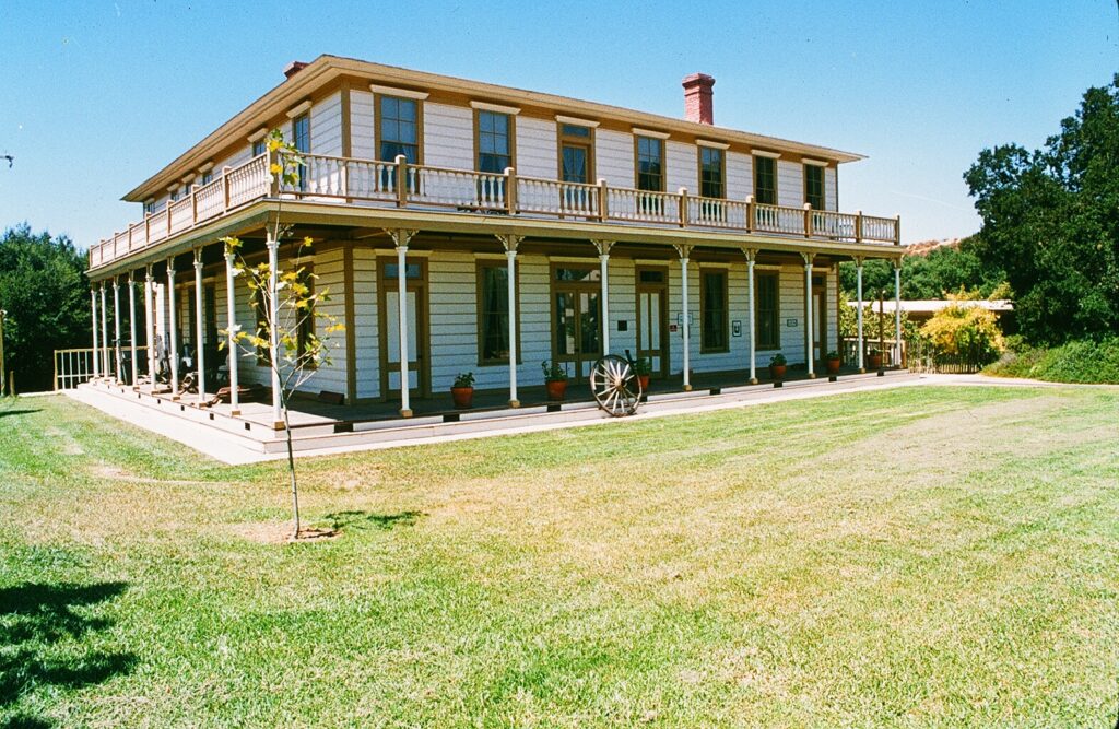 Stagecoach Inn with wraparound porch and historical architecture, surrounded by a grassy lawn, taken in 1985.