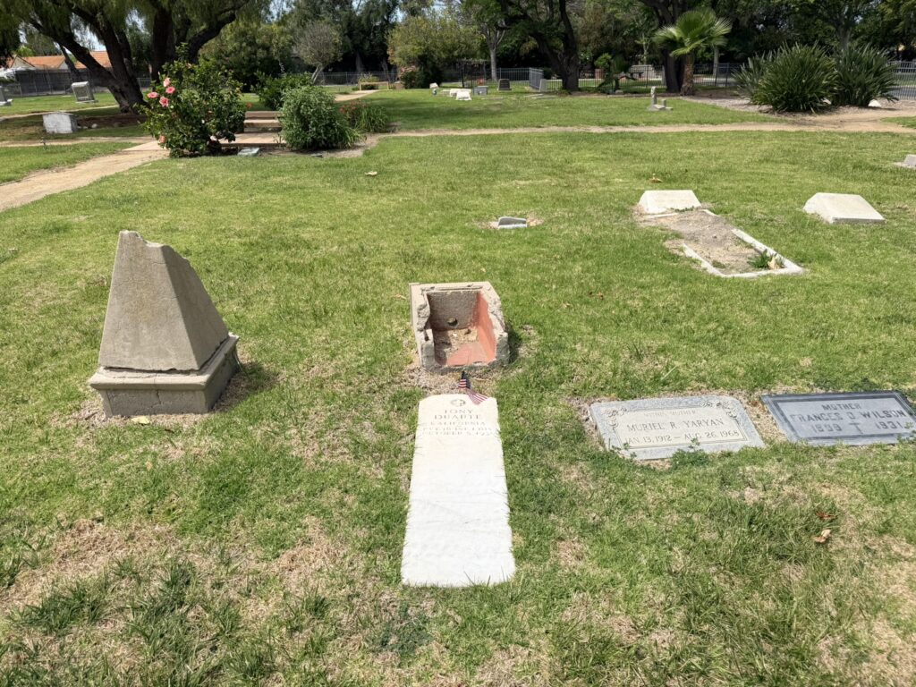 Grave markers in a grassy cemetery, including a broken pyramid monument, a small grave with an American flag, and inscribed stones, labeled "Markers of a Forgotten Era, 2026".