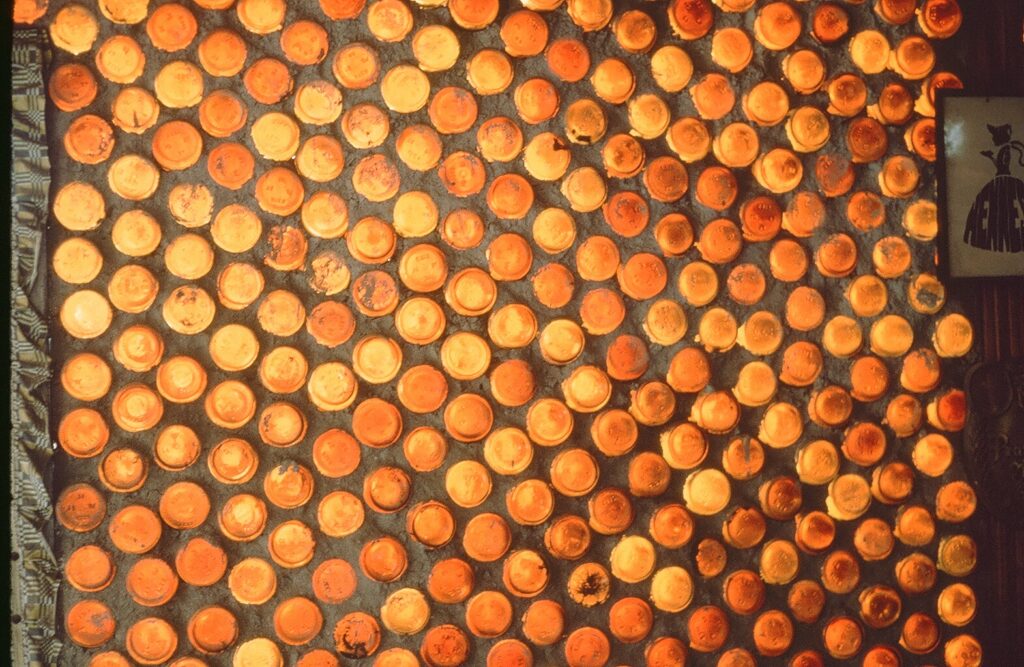 Detail photo from the 1980s showing a wall covered in a dense grid of circular orange and yellow objects.