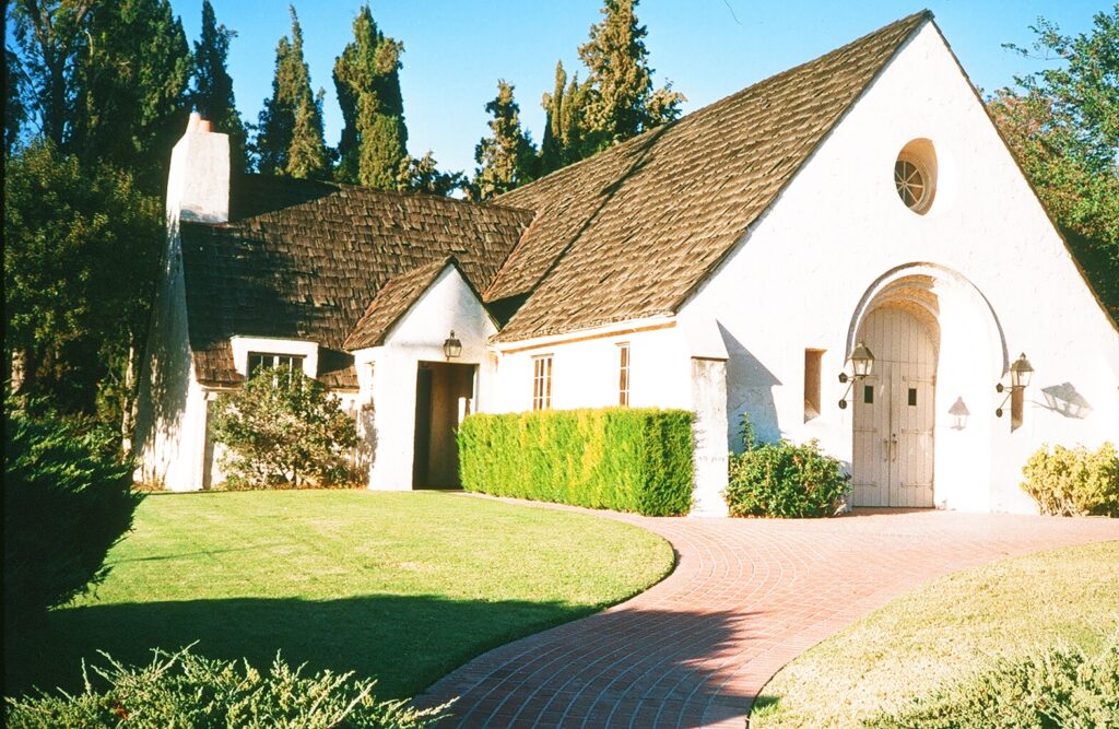 White church building with arched entrance, round window, brick pathway, and green lawn, constructed in 1985.
