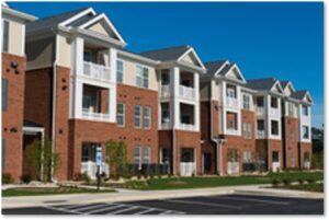 Multi-story affordable housing complex with brick and beige facades, balconies, and landscaped grounds in a high-density residential area.