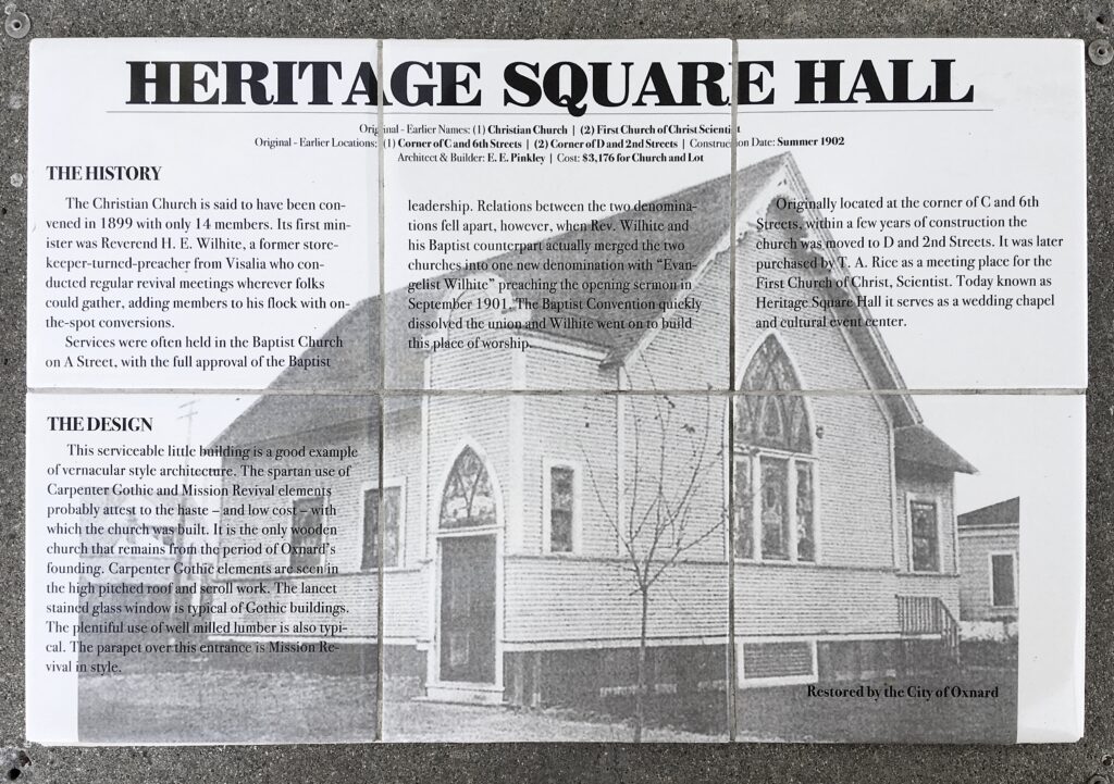 Information panel at Heritage Square (2022) detailing Heritage Square Hall's history (1899 founding, denomination changes) and architectural design (Carpenter Gothic/Mission Revival), with a black-and-white photo of the building, restored by the City of Oxnard. Credit: Craig Baker.