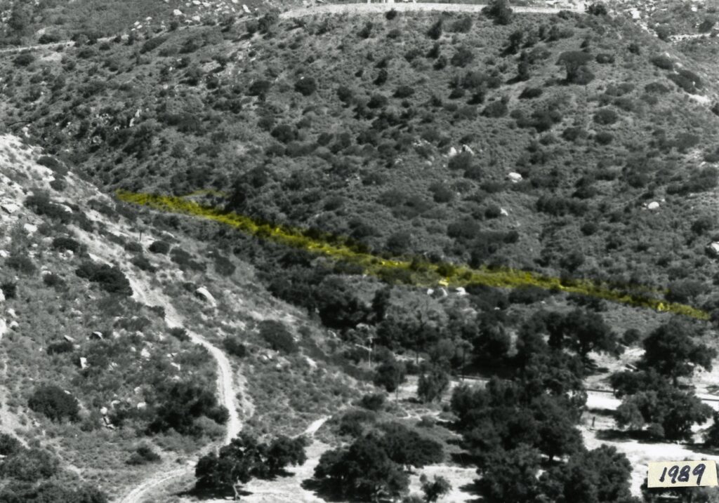 Black-and-white aerial photograph of a hilly landscape with a yellow-highlighted historical Stagecoach Road; "1989" marked in the bottom right corner.