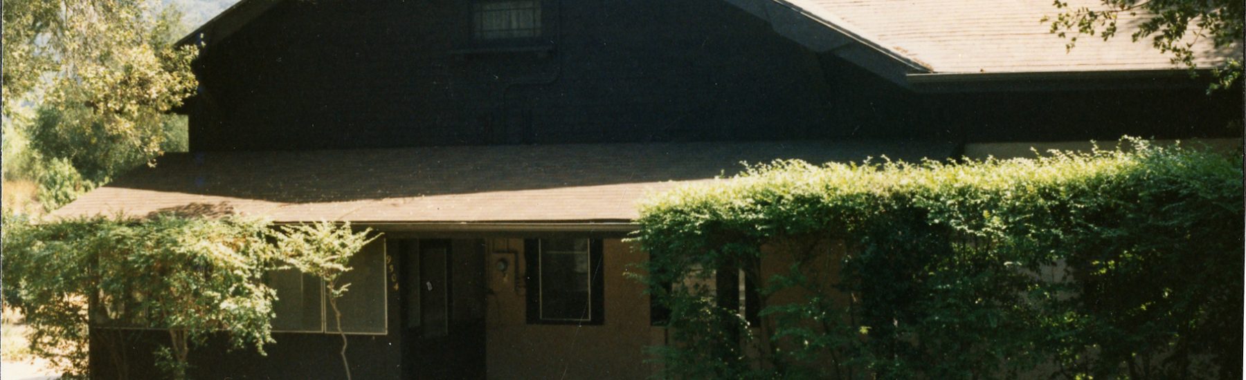 A historical house surrounded by greenery and trees.