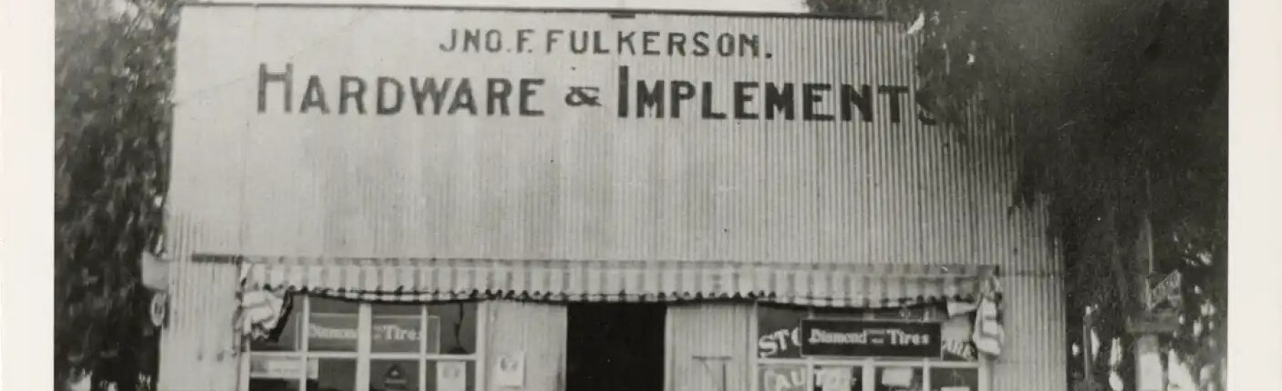 Black-and-white vintage photograph of J.N.O.F. Fulkerson's Hardware & Implements store; storefront displays "Diamond Tires" and "Auto" signage.