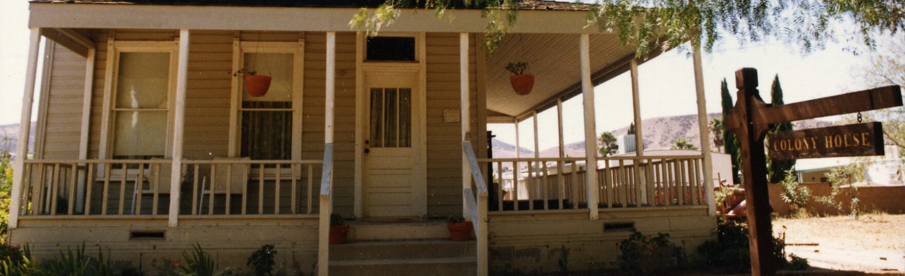 Front view of Haigh/Talley Colony House with porch, trees, and "Colony House" sign in the foreground. Image taken circa 1980s.