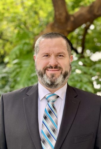 Portrait of a man with a beard, in a suit and tie.