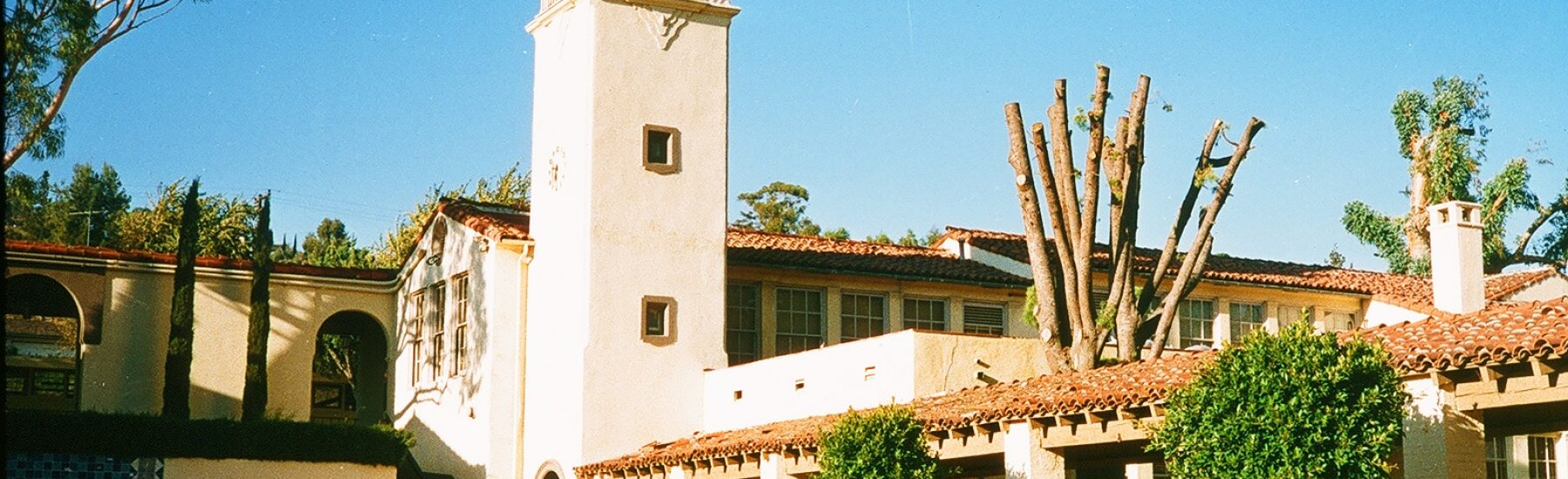 1985 Santa Paula Union High School exterior featuring a central bell tower, red-tiled roof buildings, and a fountain with a "CHARGERS" sign under a clear blue sky.